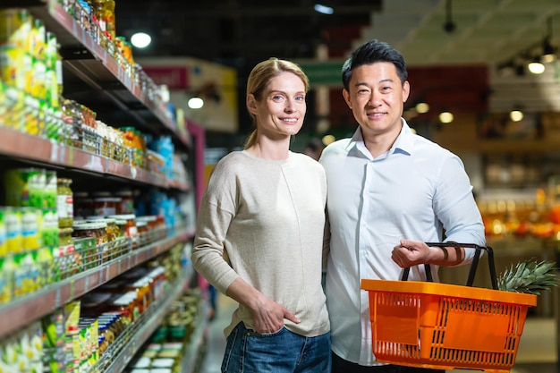 Glückliches Ehepaar Asiatischer Mann und Frau, die in die Kamera schauen und im Supermarkt bei der Auswahl von Waren lächeln