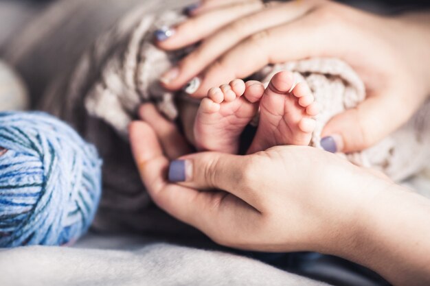 Glückliches Familienkonzept. Babyfüße in Mutterhänden. Mutter und ihr Kind. Schönes konzeptuelles Bild der Mutterschaft.