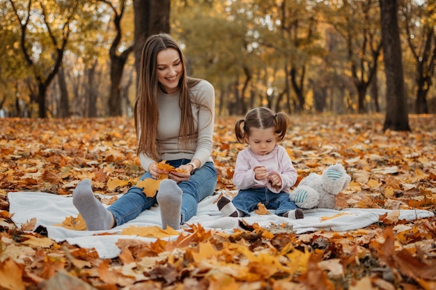 Glückliches Familienmutter- und Kleinkindbabymädchen, das draußen im Herbstpark kleines Mädchen und ihre Mutter in spielt