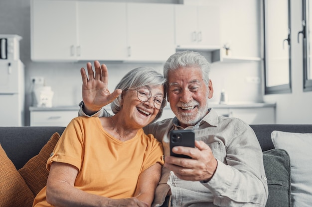 Glückliches Familienpaar im Ruhestand nutzt Mobiltelefon für Videoanrufe, unterhält sich mit Verwandten und erhält gute Nachrichten, hat Spaß beim Lächeln und Lachen. Unbeschwerte ältere Rentner chatten online auf cellxA