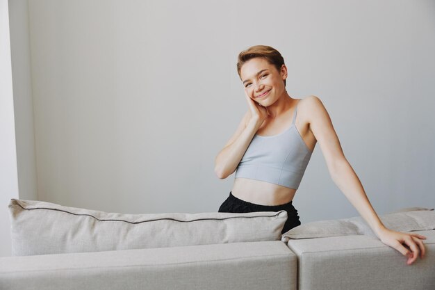 Glückliches Frauenlächeln, das zu Hause auf der Couch liegt und sich an einem Wochenende zu Hause mit einem kurzen Haarschnitthaar ohne Filter auf einem weißen Hintergrund entspannt