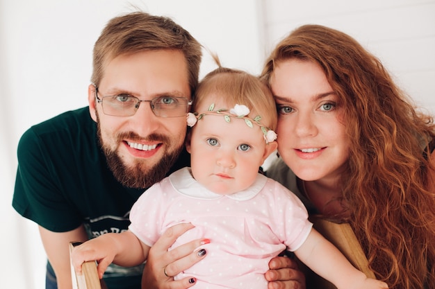 Glückliches fröhliches Paar, das mit Baby zu Hause spielt