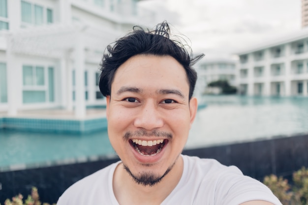 Glückliches Gesicht des asiatischen Mannes selfie sich mit Luxusresort.