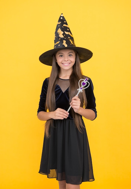 Glückliches Halloween-lächelndes Kind im Hexenhut Kind halten Zauberstab Hexerei und Verzauberung Kindheit Herbstferien Teenager-Mädchen bereit, Party-Kostüm-Party-Spaß zu feiern