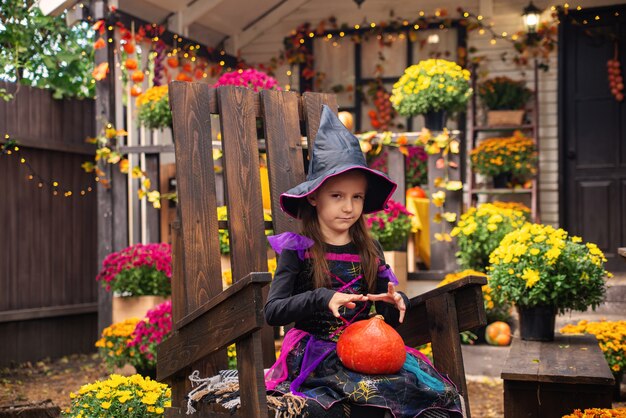 glückliches Halloween-Mädchen in Hexenkostümen, das sich im Herbst in der Nähe des Hauses amüsiert