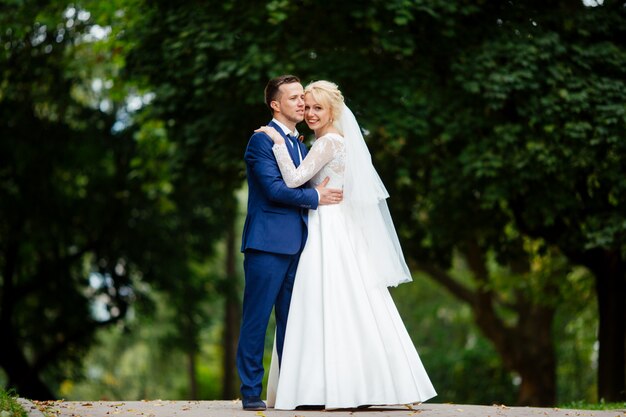 Glückliches Hochzeitspaar, das im Park geht