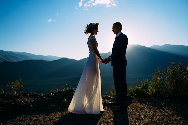 Glückliches Hochzeitspaar, das über der schönen Landschaft mit Bergen bleibt