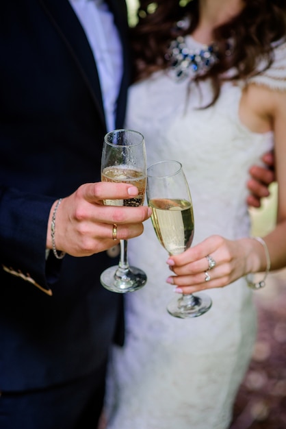 Glückliches Hochzeitspaar wirft mit Sektkelchen im Park auf