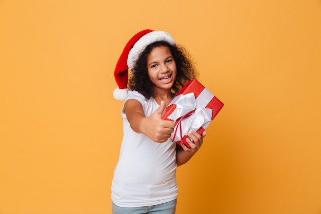 Glückliches hübsches kleines Mädchen, das Weihnachtsmannhut des Weihnachtsmanns trägt