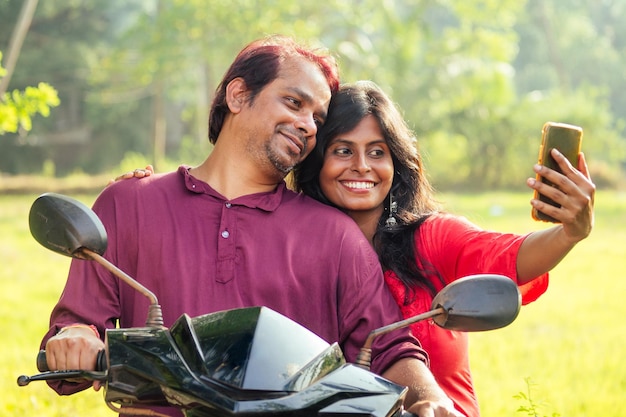 Glückliches indisches Ehepaar, das auf dem Motorrad im tropischen Dschungel in Goa Indien fährt