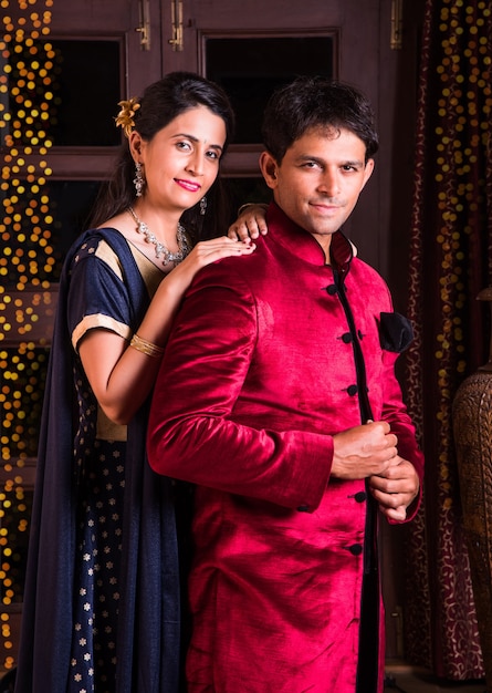 Glückliches indisches junges Paar in Namaskara oder gefaltete Hände posieren auf dem Diwali-Festival und begrüßen Gäste