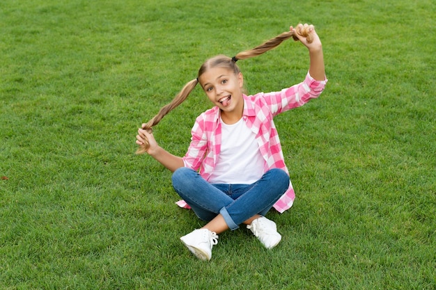 Glückliches jugendlich Kind, das Spaß auf dem grünen Gras im Freien hat