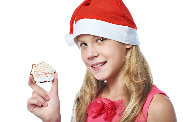 Foto glückliches jugendlich mädchen in der roten kappe mit dem weihnachtsplätzchen lokalisiert