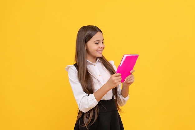 Glückliches jugendlich Mädchen in der Schuluniform, die Buchliteratur liest