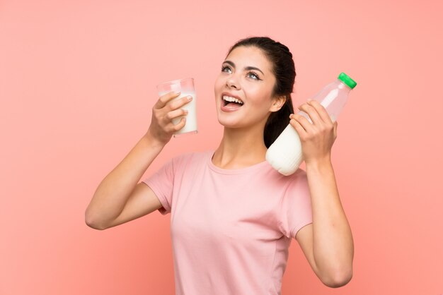 Glückliches jugendlichmädchen über der lokalisierten rosa wand, die frühstücksmilch hat