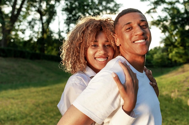 Glückliches junges afroamerikanisches Paar, das zusammen im Park steht und sich umarmt