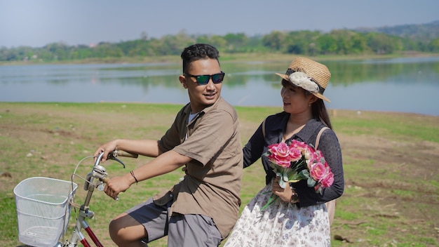Glückliches junges asiatisches Paar, das im Sommer Blumen hält