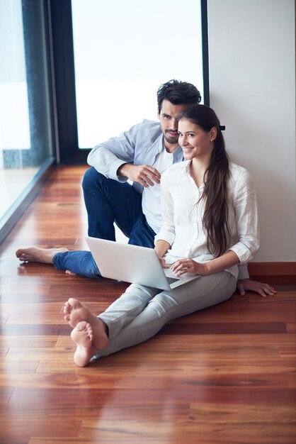 glückliches junges entspanntes paar, das an laptop-computer im modernen wohninnenraum arbeitet