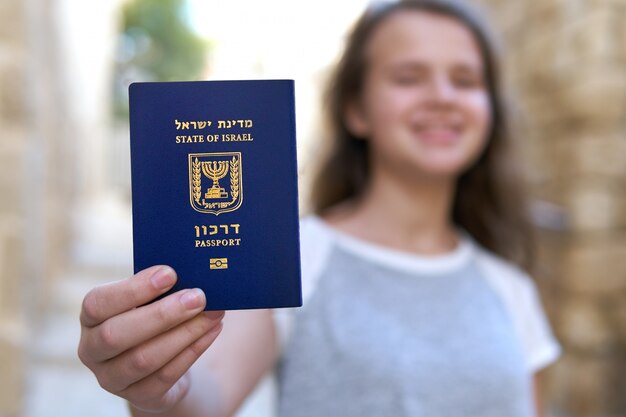 Glückliches junges Mädchen, das den Pass des Staates Israel zeigt, der ihn in der Hand hält