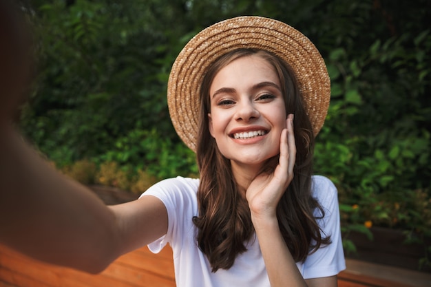 Glückliches junges Mädchen, das ein selfie mit ausgestreckter Hand am Park draußen nimmt