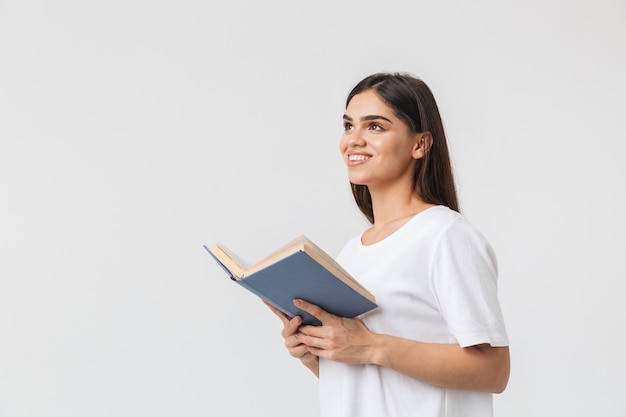 Glückliches junges Mädchen, das isoliert auf Weiß steht und ein Buch liest