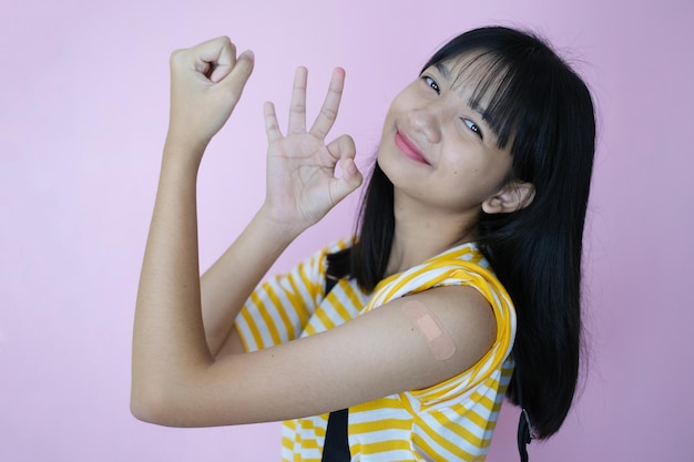 Glückliches junges Mädchen, das nach der Impfung Schulter zeigt.