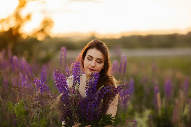 Glückliches junges Mädchen lächelnd, Hände im Lavendel haltend. Weichzeichner, Nahaufnahme