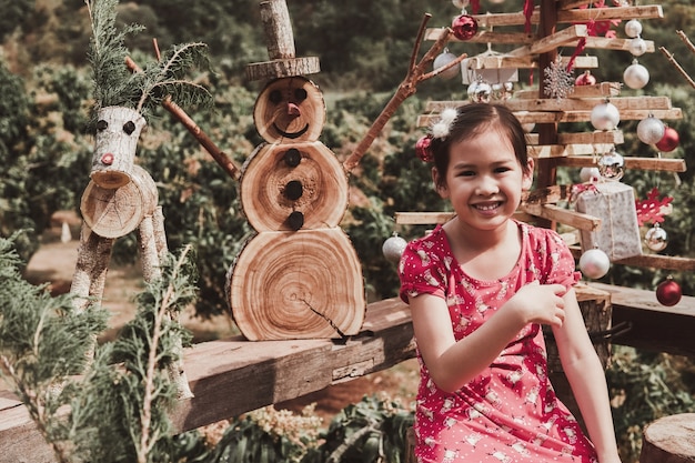 Foto glückliches junges mädchen mit festlicher weihnachtsdekoration aus wiederverwendbarem holz