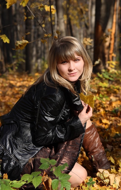 glückliches junges Mädchen mit gelbem Blatt auf herbstlichem Hintergrund