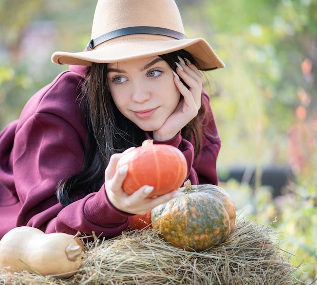 Glückliches junges Mädchen mit Kürbis im Herbstgarten