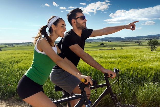Glückliches junges Paar auf einem Fahrrad fahren auf dem Land