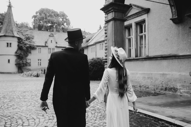 Glückliches junges Paar Bräute in Hüten Junges Mädchen in einem weißen Brautkleid und Hut mit einem Blumenstrauß Bräute im Schloss Braut und Bräutigam