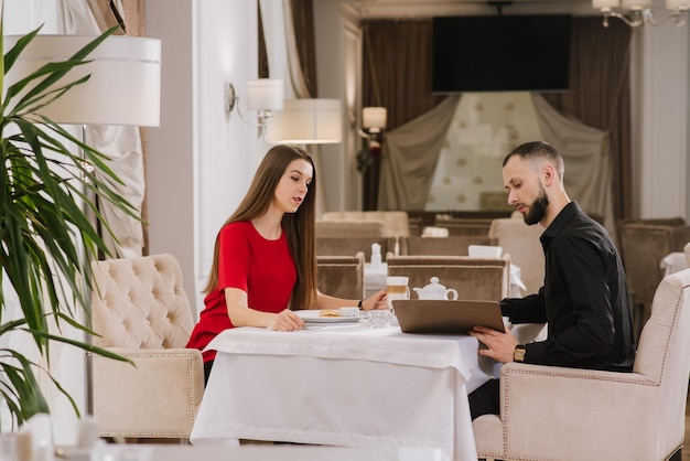 Glückliches junges Paar, das im Restaurant sitzt und sich unterhält