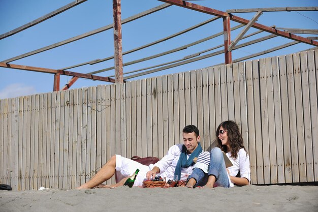 glückliches junges paar, das picknick am strand genießt und in den sommerferien eine gute zeit hat