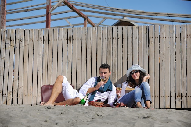 glückliches junges paar, das picknick am strand genießt und in den sommerferien eine gute zeit hat