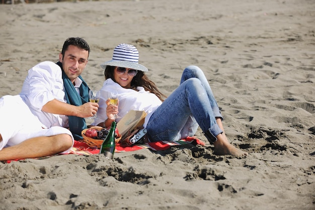 glückliches junges paar, das picknick am strand genießt und in den sommerferien eine gute zeit hat