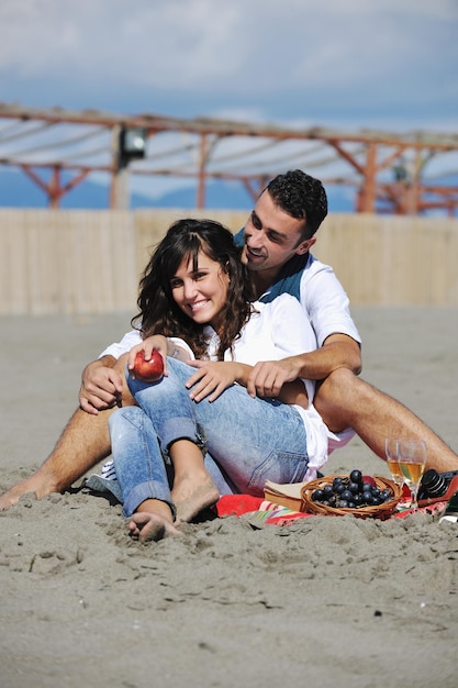 glückliches junges paar, das picknick am strand genießt und in den sommerferien eine gute zeit hat