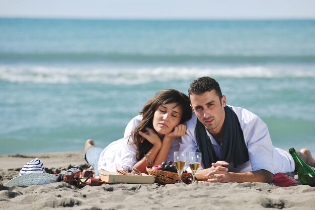 glückliches junges paar, das picknick am strand genießt und in den sommerferien eine gute zeit hat