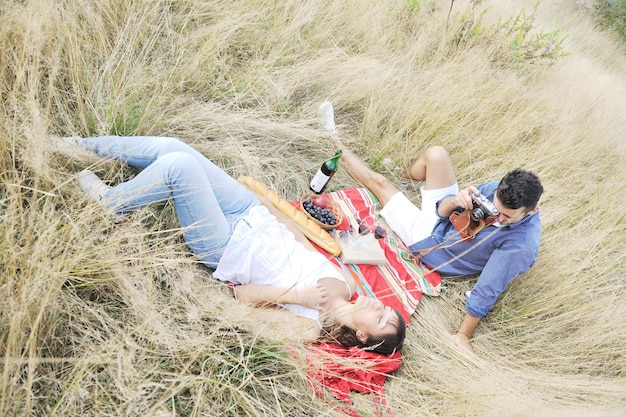 glückliches junges paar, das picknick auf dem land auf dem feld genießt und eine gute zeit hat