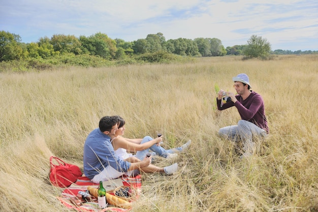 glückliches junges paar, das picknick auf dem land auf dem feld genießt und eine gute zeit hat