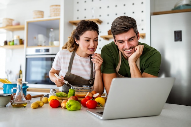 Glückliches junges Paar, das zu Hause Essen in der Küche zubereitet. Gesundes Essen, Menschenkonzept