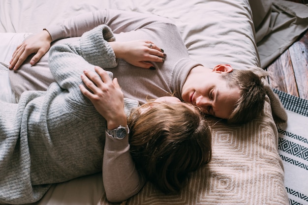 Glückliches junges Paar, das zu Hause im Bett bleibt