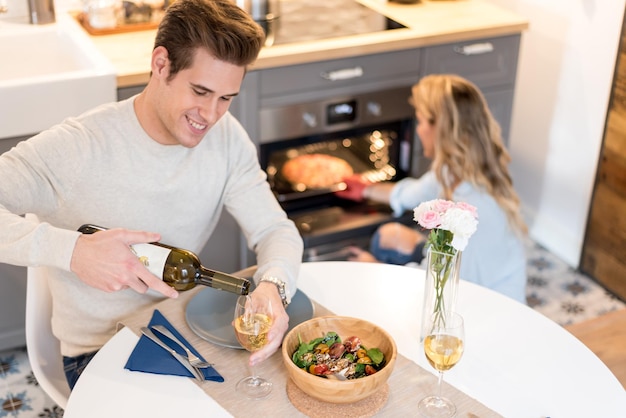 Glückliches junges Paar, das zu Hause zu Abend isst, Frauen, die eine Pizza aus dem Ofen nehmen