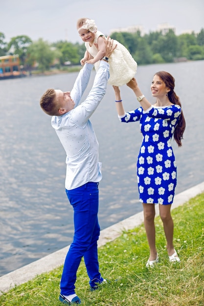 Glückliches junges Paar erhöht in den Händen eines Kindermädchens Wasser. das Mädchen im blauen Kleid, Jungenhemd im Marinestil