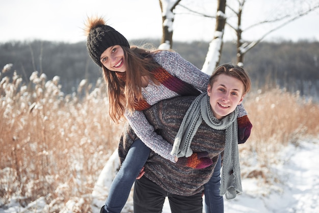 Glückliches junges Paar hat Spaß auf frischem Schnee am sonnigen Tag des schönen Winters im Urlaub