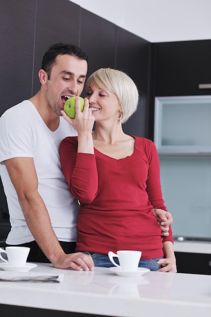 glückliches junges paar hat spaß in der modernen küche drinnen und bereitet frischen obst- und gemüsesalat zu