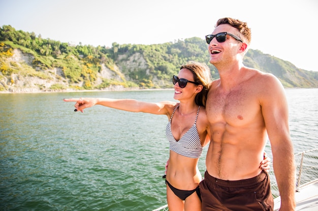 Glückliches junges Paar in der Umarmung auf Segelboot, das auf dem Meer schwimmt. Junge Leute, die Spaß im Urlaub haben, exklusiven Urlaub