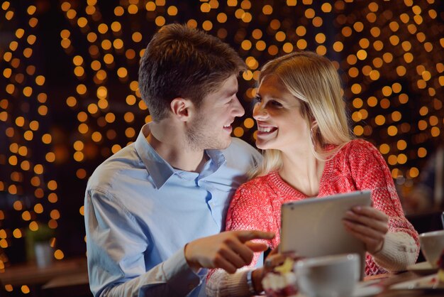 glückliches junges Paar mit einem Tablet-Computer im Restaurant