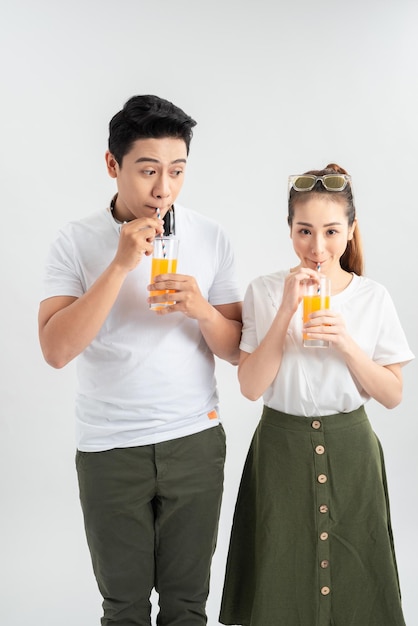 Glückliches junges paar mit gläsern orangensaft isoliert auf weißem hintergrund