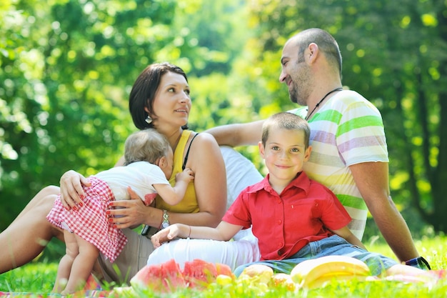 Glückliches junges Paar mit ihren Kindern haben Spaß am schönen Park im Freien in der Natur